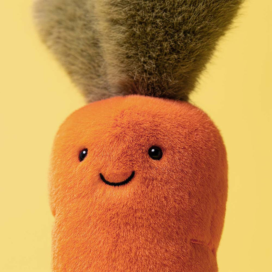 Jellycat Amuseables Carrot detalj – nærbilde av smilende ansikt og oransje tekstur